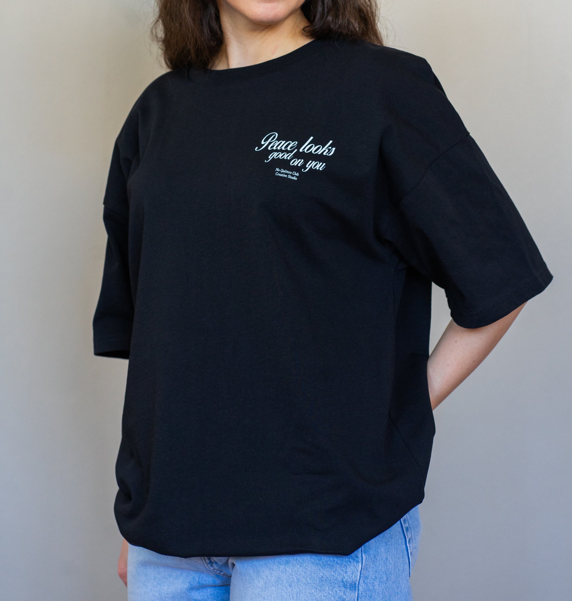 Minimalist oversized t-shirt in black with “Peace Looks Good on You” quote, made from 100% organic cotton for elevated everyday wear.