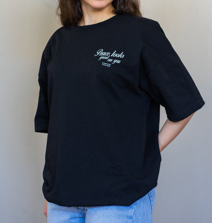 Minimalist oversized t-shirt in black with “Peace Looks Good on You” quote, made from 100% organic cotton for elevated everyday wear.